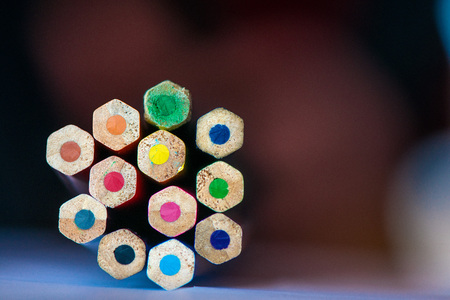 Pile of sharp coloured drawing pencils on table. Rainbow colors - red, yellow, blue, green, purple....