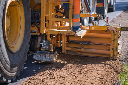 Road construction workers repairing highway road on sunny summer day. Loaders and trucks on newly...