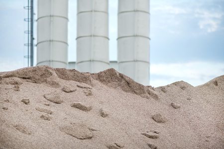 Large piles of construction sand and gravel used for asphalt production and building. Limestone quarry, mining rocks and stones. Factory in the background. Empty space for text of logoの写真素材