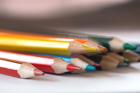 Pile of sharp coloured drawing pencils on table. Rainbow colors - red, yellow, blue, green, purple. Concept of art, crafts and kids having funの写真素材
