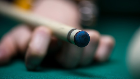 Sport billiard balls on green billiard table in pub. Player is about to hit the ball, focusing on his shot. On going billiard game. Competitive players trying to find out the winner of the round.の写真素材