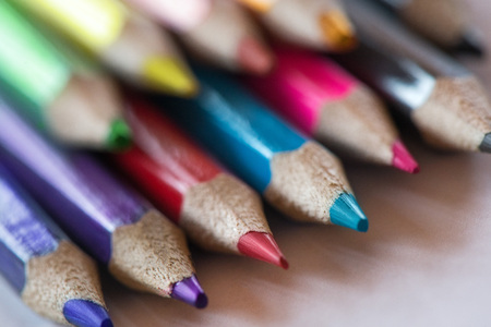 Pile of sharp coloured drawing pencils on table. Rainbow colors - red, yellow, blue, green, purple. Concept of art, crafts and kids having fun.の写真素材