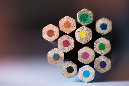 Pile of sharp coloured drawing pencils on table. Rainbow colors - red, yellow, blue, green, purple....