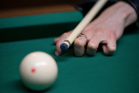 Sport billiard balls on green billiard table in pub. Player is about to hit the ball, focusing on his shot. On going billiard game. Competitive players trying to find out the winner of the round.の写真素材