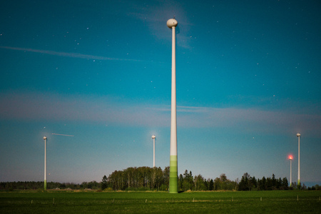 Abstract shot of wind turbines in the meadow on starry night sky background. Falling stars. Rural...