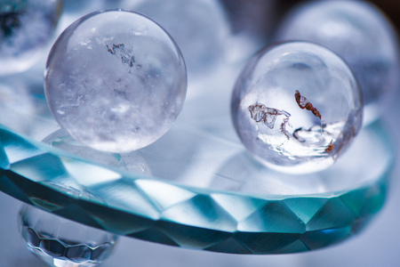 Macro shot of transparent crystal balls with colorful ornaments and sun reflections in it, on turquoise glass pad. Fortune telling. Love, money, luck, successの写真素材