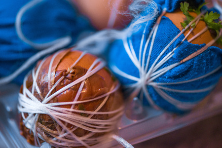 Easter eggs prepared for dyeing in onions peels, decorated with natural fresh leaves, plants, rice, colorful fabric and tied with white threads.の写真素材
