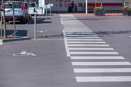 Newly made parking lot next to shopping mall in city centre with green areas and pedestrian crossing. Arrows and signs on asphalt showing rules and directionsの写真素材