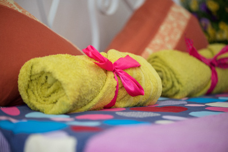 A king sized bed prepared for a newly wed couple with fresh yellow towels and fresh bed linens. Pink ribbon decorations.の写真素材