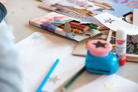 Creative workshop for kids. Drawing on white paper at school. Glue, colorful pencils, star and christmas tree shaped paper cutter on table. having fun.の写真素材