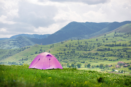 Tent is built in meadow. Beautiful, fresh morning in mountain landscape next to medieval village.の写真素材