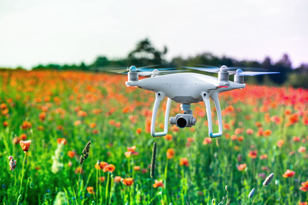 White quadrocopter, is flying high in the air, to take photos and record footage from above, in red...