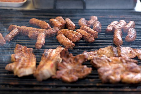 Street food being made in state fair. Traditional meat and sausages grilled in open air market for people. First barbecue party outdoors in springの写真素材