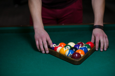 Sport billiard balls set arranged in shape of triangle on green billiard table in pub. Players are ready for the first hit of the round to start the billiard gameの写真素材