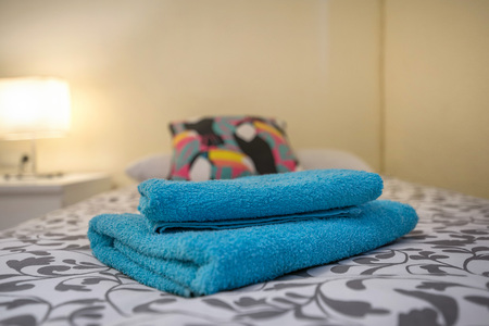 A king sized bed prepared for a newly wed couple with fresh towels and fresh bed linens. Cosy light...