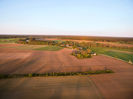 Aerial drone view of old farmhouses, barns, houses and trees during sunset. Calm, peaceful landscape of countryside. Concept of agriculture industryの写真素材