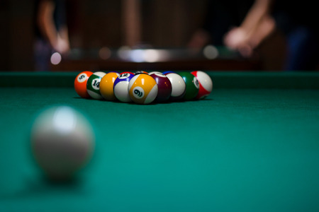 Sport billiard balls set arranged in shape of triangle on green billiard table in pub. Players are ready for the first hit of the round to start the billiard game.の写真素材