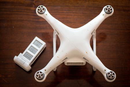 Dirty drone without propellers after filming and photographing an event standing on wooden table...