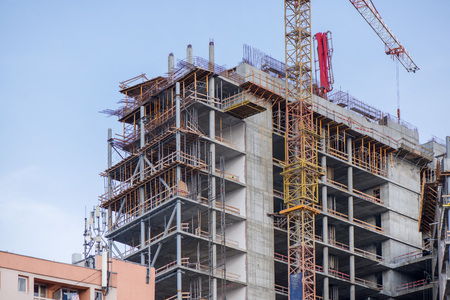 Close up of crane doing construction work on block building. New buildings being constructed....