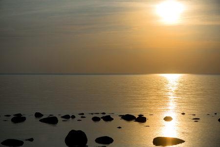 Beautiful sunset or sunrise landscape over rocky beach, seashore with big stones. Concept of relaxing family holidays, camping in nature, recreation and relaxing.の写真素材