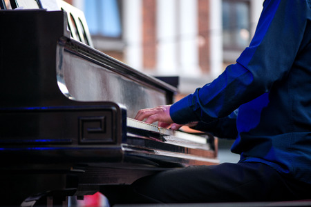 Male musician on stage playing piano. Crowded venue. Audience enjoying romantic and relaxing evening.の写真素材
