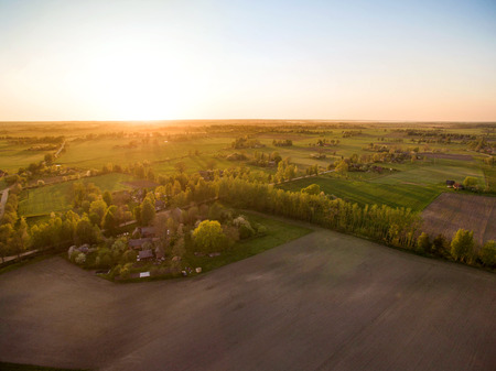 Aerial drone view of old farmhouses, barns, houses and trees during sunset. Calm, peaceful landscape of countryside. Concept of agriculture industryの写真素材