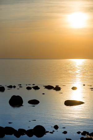 Beautiful sunset or sunrise landscape over rocky beach, seashore with big stones. Concept of relaxing family holidays, camping in nature, recreation and relaxing.の写真素材