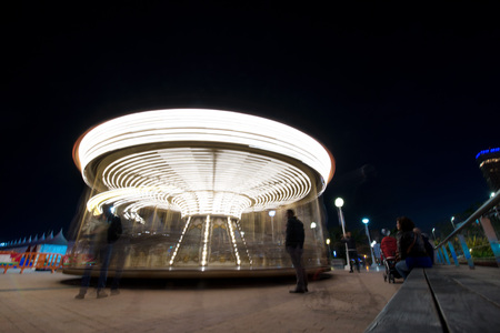 Abstract, long exposure shot of spinning Children's vintage Carousel at an amusement park in the evening and night illumination. Beautiful, bright carousel in Alicante, Spainの写真素材