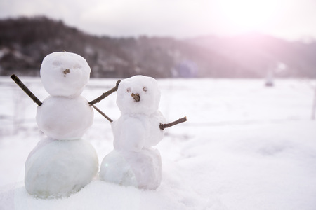 Two real tiny, little snowman in nature in snowy, cold day in mountains. Concept of beautiful winter and kids or family having fun on holidays. Merry Christmas.の写真素材