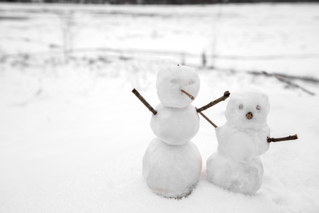 Two real tiny, little snowman in nature in snowy, cold day in mountains. Concept of beautiful winter and kids or family having fun on holidays. Merry Christmas.の写真素材