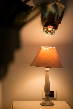 Bright eco light in the corner of a modern bedroom with stylish interior design elements, storage boxes, woven baskets on wall to set warm, homely mood and atmosphere.の写真素材