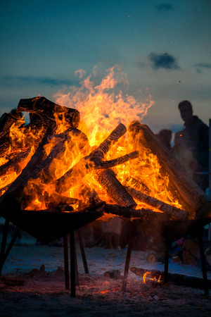 Large burning bonfire with soft glowing flame and sparkles flying all around. Romantic summer evening, people relaxing and enjoying calmness at the seaside during the Night of ancient lights.の写真素材
