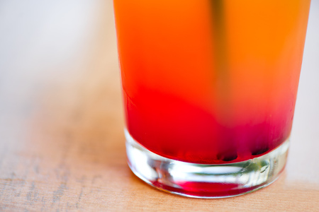 Glass of alcoholic tequila sunrise or campari and grenadine cocktail with juice in restaurant of bar. Concept of luxury holidays and vacation. Woman holding full glass of cold, refreshing beverageの写真素材