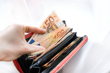 Woman holding wallet full of euro money bills and banknotes. Concept of stealing cash, rich people, savings or spending money. Counting payment.の写真素材