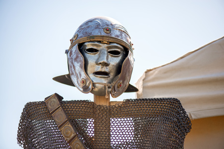 Medieval knight's iron chain armor and metal helmet on wooden cross hanger. Reenactment festival in...