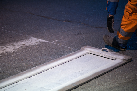 Traffic line painting. Workers are painting white street lines on pedestrian crossing. Road cones with orange and white stripes in background, standing on asphalt during road construction worksの写真素材