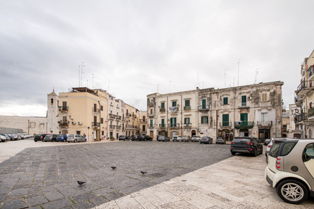 Early morning in old city in Italy, Bari. Cars and scooters parked next to apartment buildings with flower decorated balconies and facades.の写真素材