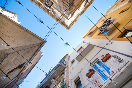 Hanging light bulbs in colorful, romantic, narrow streets of Bari, Italy. Traditional architecture...