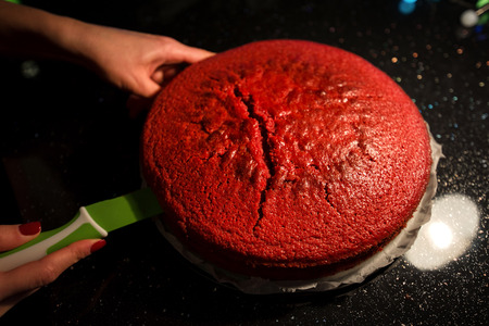 Cutting biscuits. Woman is cooking in kitchen, baking a red velvet cake. Taking out or putting a...