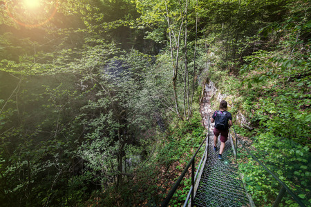 Young man is exploring underground glacier in Glaciers Cave in Apuseni mountains, Scarisoara, Romania. Walking down stairs. Concept of traveling alone, expedition and adventures in forestの写真素材