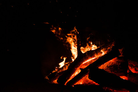 Large burning bonfire with soft glowing flame and sparkles flying all around. Romantic summer...