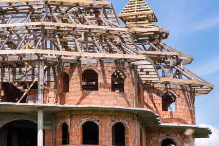 District for rich people with traditional, large gypsy house with luxury decorations and ornaments on the roof in Huedin, Romania. Houses being under construction. Concept of bankruptcy, and abandonedの写真素材