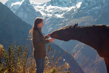 Girl with a horse in the background of mountainsの写真素材