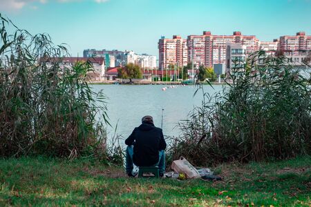 old-man fisherman on the river against the backdrop of the cityの写真素材