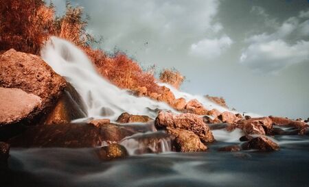 a fast waterfall near a quiet blue river