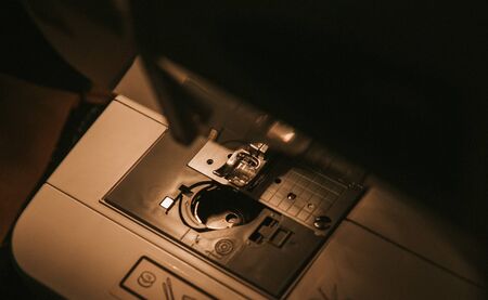 Old sewing machine with black thread scissors and needle, on a old grungy work table.の写真素材
