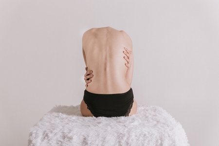 Portrait of beautiful nude young woman with long blond hair covering her breast while lying on bedの写真素材