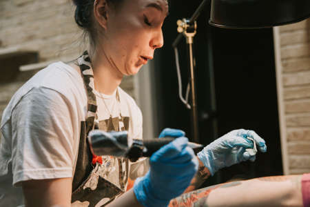 Beautiful creative master is working on new peace of big leg tattoo for customer.の写真素材