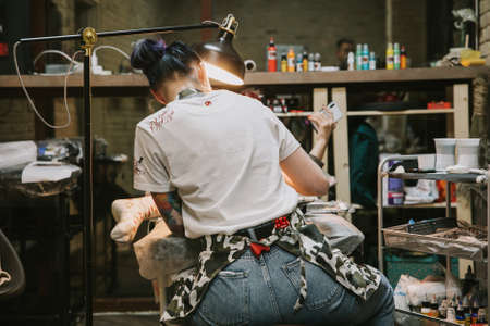 Beautiful creative master is working on new peace of big leg tattoo for customer.の写真素材