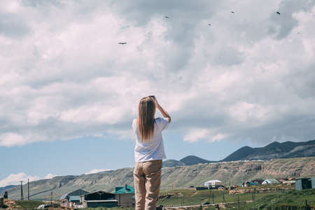 Young girl photographing birds in the mountainsの写真素材